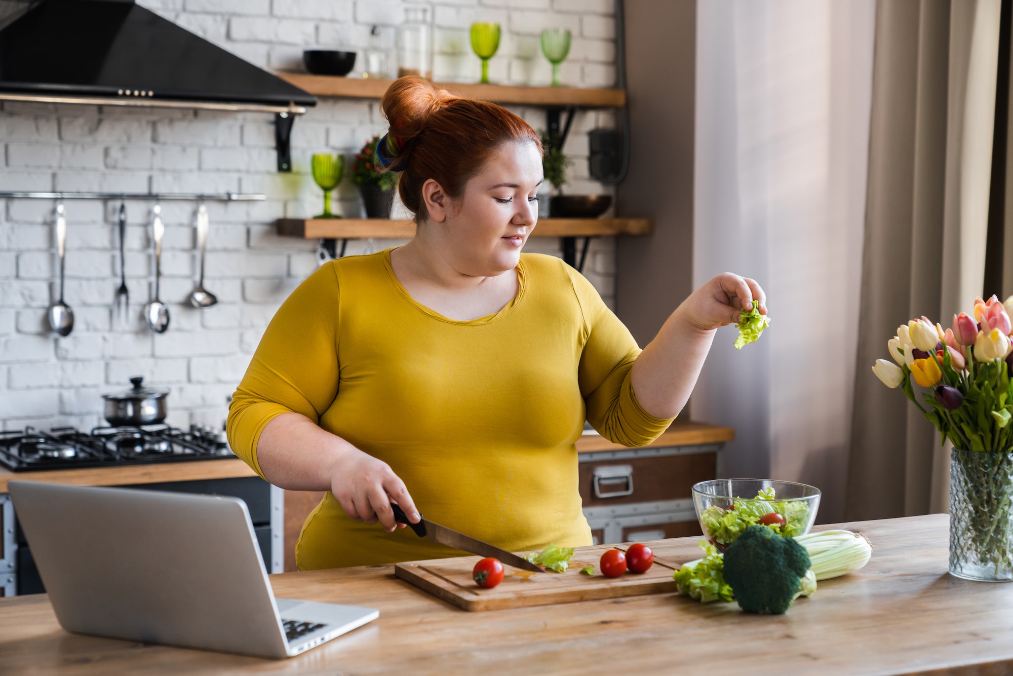 Plus size , fat caucasian woman learning to make salad and healthy food from social media